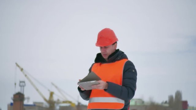 Builder Architect Man In Helmet With Tablet On Construction Site. Construction Industry Worker In Winter Building A House Lifestyle