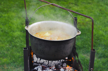 Cooking food in a pot on campfire. Summer camping concept.