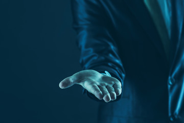 closeup of a businessman stands and extends a hand forward.