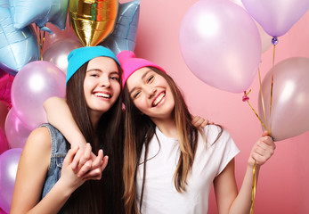 Beautiful girls with air balloons on pink background