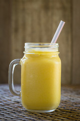 Fresh organic mango shake in glass mug on wooden table, close up