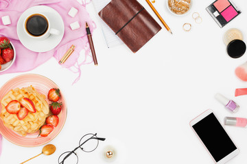 Beautiful flatlay arrangement with cup of coffee, hot waffles with cream and strawberries, smartphone with copyspace and beauty accessories: concept of busy morning breakfast, white background.