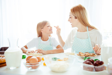 Obraz na płótnie Canvas Upbringing forms tasty fooling yummy event joke forefinger pointing concept. Cheerful lovely mommy and small playful cute tender girl making sweets and cookies cakes, pies at home in light kitchen