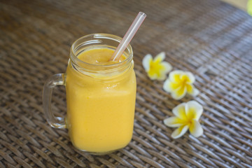Fresh organic mango shake in glass mug on wooden table, close up