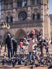 Girl feeding pigeons in the square in front of the cathedral of Notre Dame