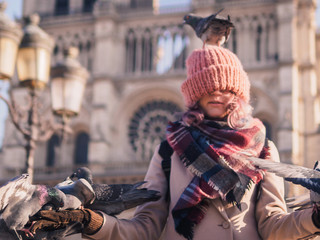 Girl feeding pigeons in the square in front of the cathedral of Notre Dame