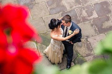 Bride and groom hug in the courtyard of the old castle and look at each other in the eye. Wedding day.  Young smiling beautiful couple.