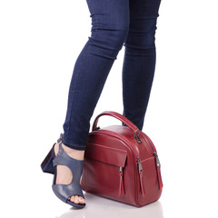 Female legs in jeans and in blue sandals shoes with red leather bag handbag