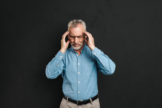 Image Of Old Man 60s With Grey Hair And Beard Having Headache And Rubbing Temples In Fatigue, Isolated Over Black Background