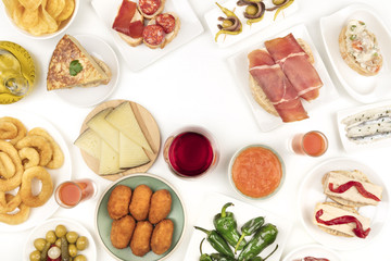 An overhead photo of Spanish tapas, forming frame on white with copy space