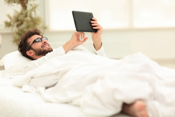 closeup.sleepy man looking at the screen of a digital tablet.