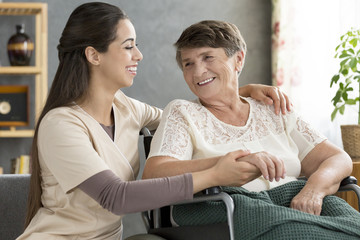 Nurse supporting happy elderly woman