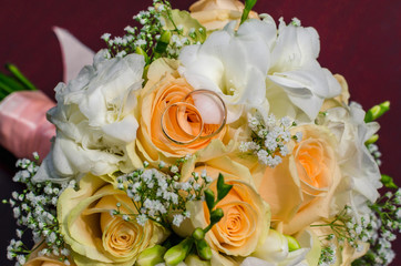 Bouquet of flowers of the bride. Wedding bouquet of flowers with wedding rings. Bouquet of flowers of peach-colored roses, eustomises.