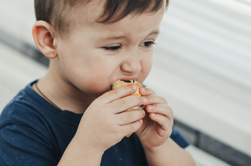 Beautiful baby sitting in the kitchen eating a delicious tube of condensed milk