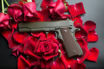Gun and red roses flower on dark background
