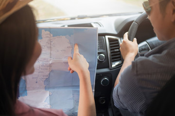 Couple in car with map. Man at the wheel.