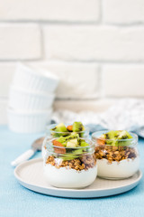 Kiwi granola parfait with nuts and greek yogurt in glass jars. Selective focus, space for text.