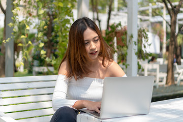 Beautiful young woman watching something on laptop in the garden.