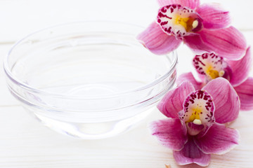 Spa and wellness setting with orchid, oil on wooden white background closeup