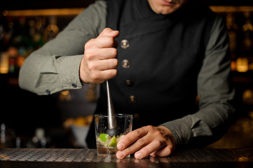 Barman squeezing juice from fresh lime using citrus press