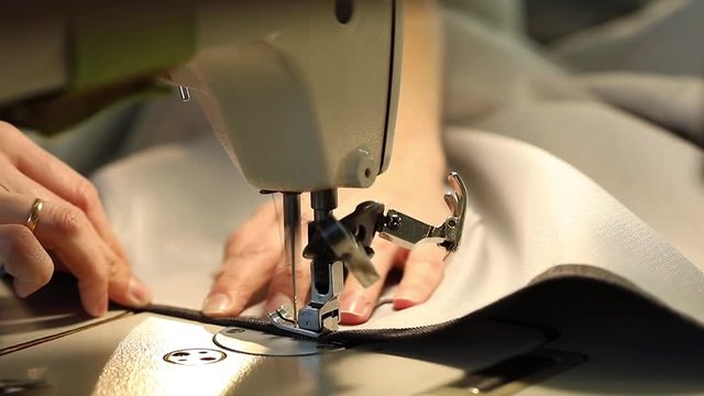 Woman working at a sewing machine, needle sewing machine, female hands, Slow Motion Video, close-up, shallow depth of field, industrial sewing machine