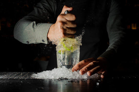 Barman squeezing juice from fresh lime using citrus press and splashing it out