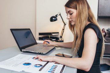 Obraz na płótnie Canvas Female businesswoman readind financial report analyzing statistics pointing at pie chart working at her desk