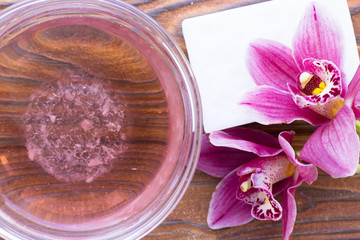 Spa and wellness setting with orchid, oil and soap on wooden dark background closeup