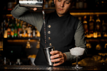 Barman mixing drinks for making a cocktail with campari