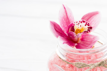 Spa and wellness setting with orchid and rose sea salt in a can on wooden white background closeup