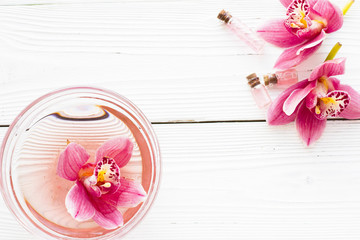 Spa and wellness setting with orchid and oil on wooden white background closeup