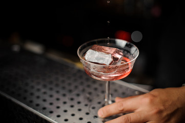 Male hand holding a cocktail glass with alcoholic drink