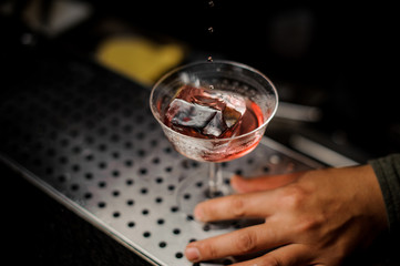 Male hand holding a cocktail glass with sweet alcoholic drink