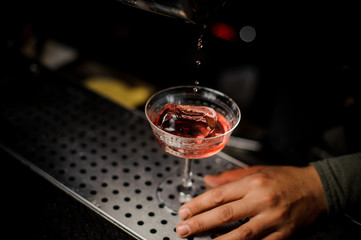Bartender pouring campari liquor into the cocktail