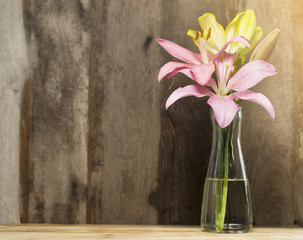 Pink lilies are on wooden background.