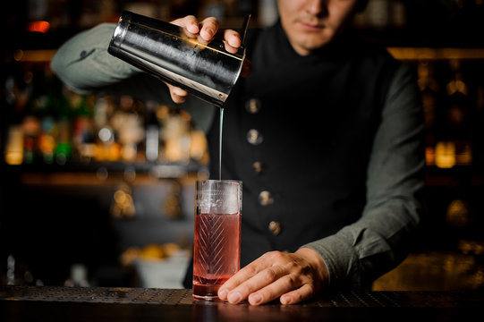 Bartender making a summer light sour cocktail with pink peach liquor