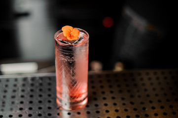 Summer light sour cocktail with pink peach liquor decorated with flower