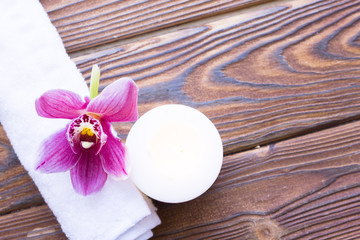 Obraz na płótnie Canvas Spa and wellness setting with orchid, towel and candle on wooden dark background closeup