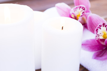 Spa and wellness setting with orchid, towel and candle on wooden dark background closeup