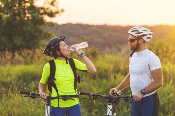 Cyclists man and woman stopped to drink water on the journey.