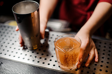 Female hands holding a shaker and a cocktail glass decorated with cinnamon