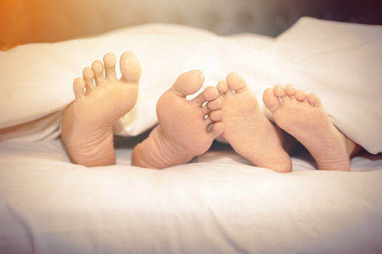 Family on the bed at home with their feet showing