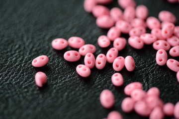 Scattered twin beads pink color on a dark surface close up