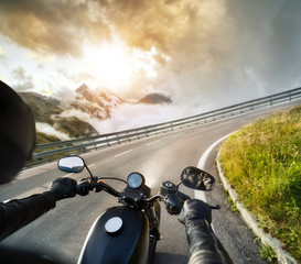 POV of motorbiker holding steering bar, riding in Alps