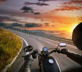 POV of motorbiker holding steering bar, riding in Alps