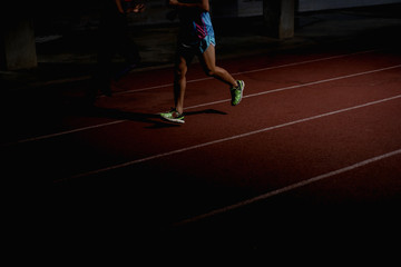 Athletics people running on red running track at night