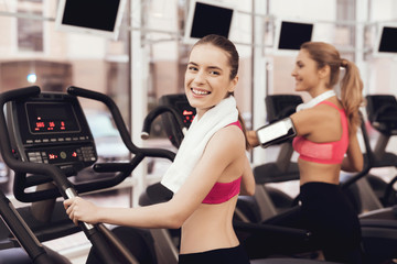 Fototapeta na wymiar Woman and girl running on treadmill at the gym. They look happy, fashionable and fit.