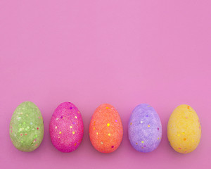 Decorated colorful Easter eggs on pink paper background with space for text. Trendy minimal pop art style and colors.