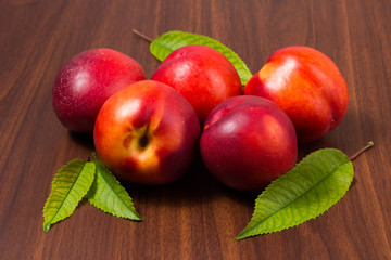 Peaches with leaves on a dark wooden table