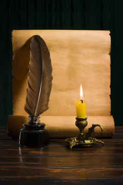 The concept of education and writing, an inkwell with a pen and a candle on the background of a roll of parchment
